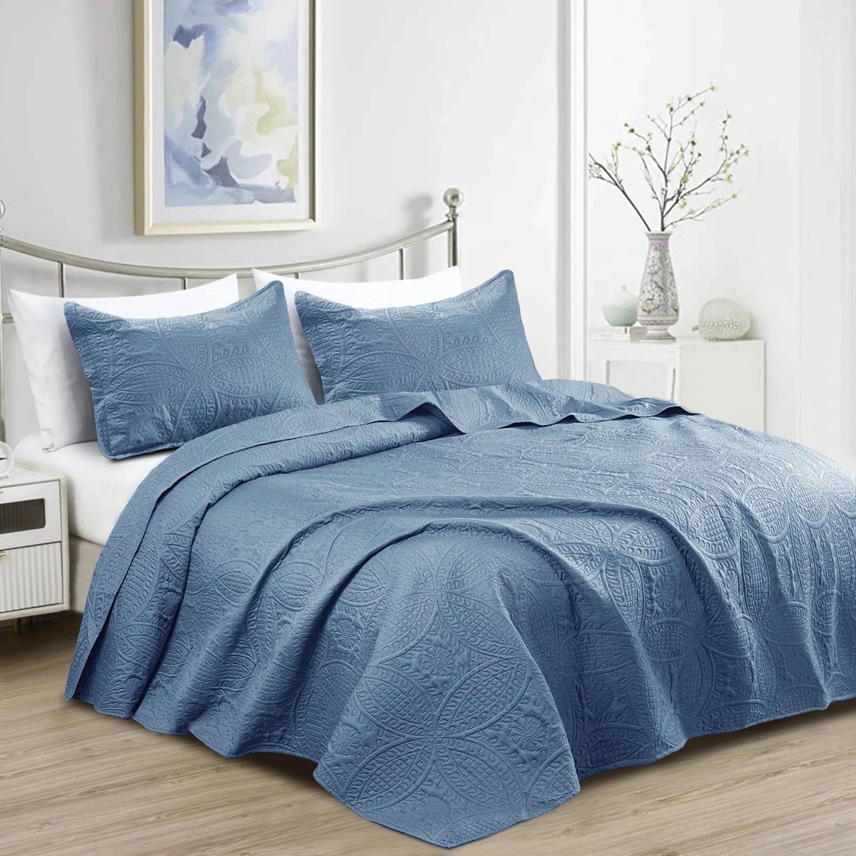 Blue quilted bedspread set with matching pillowcases and floral coin pattern