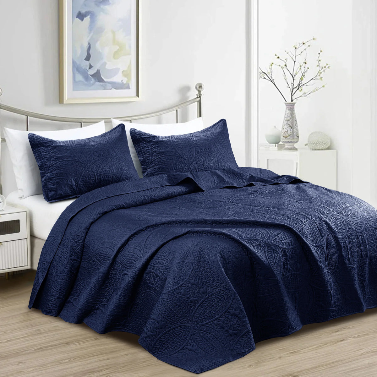 Navy blue quilt bedding set with embossed floral pattern and matching pillowcases